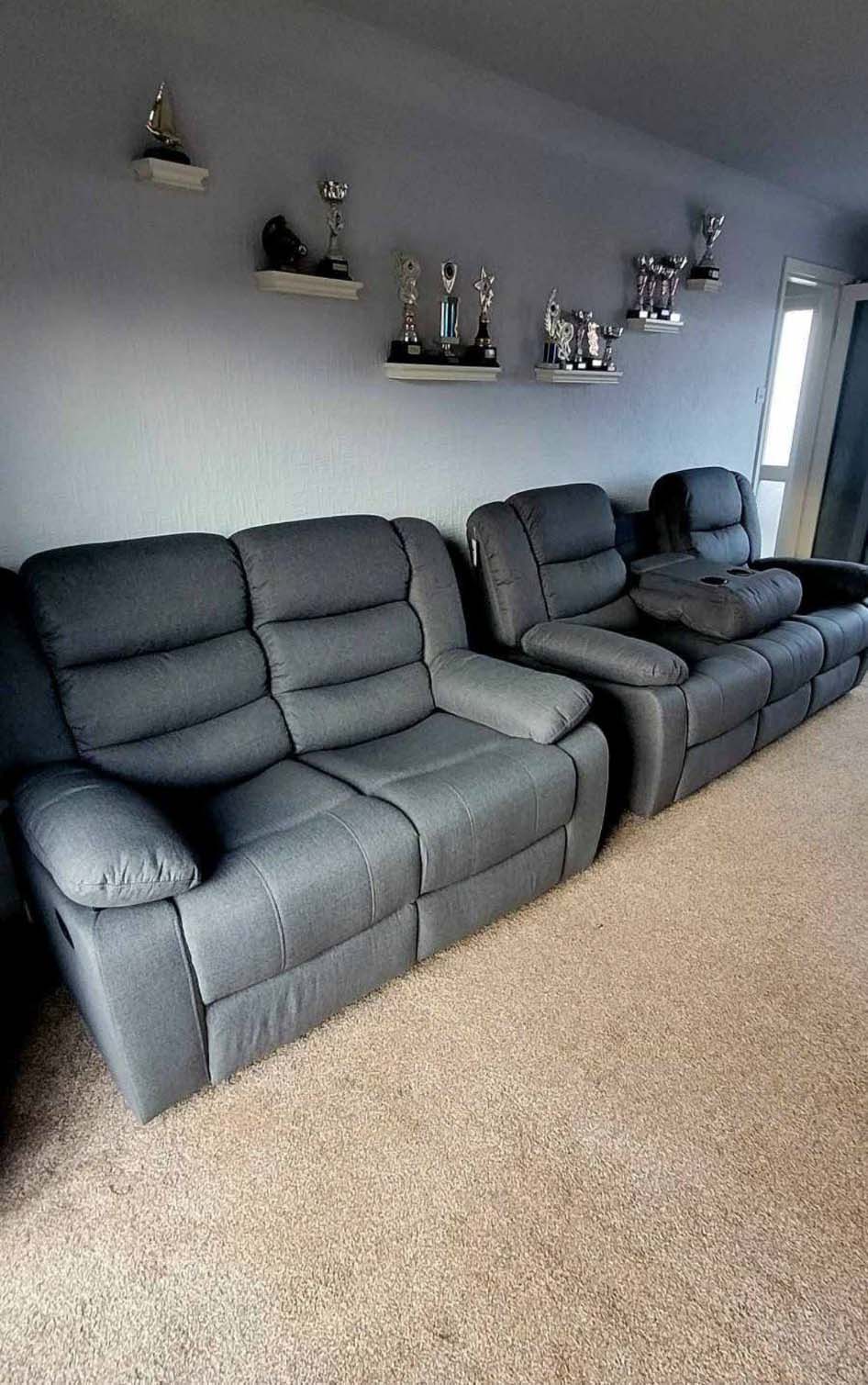 Dark grey recliner sofas in living room with trophies on the wall